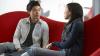 Photograph of two people sitting on a sofa chatting