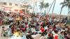 An engaged audience watches a talk outside beside palm trees and a blue sky at WOW Karachi.