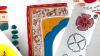 Drawings on paper in preparation for making an activity to go in the pack. There is a pretty border with a floral pattern, with different doodles in bright orange, bright blue, grey pink pastel and green on white paper.