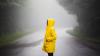 Woman in a yellow raincoat standing on a rural highway in Canada