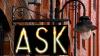 Illuminated sign that says 'ask' on the side of a brick building