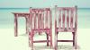 Two wooden chairs and a table on a beach