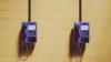 Two purple public phones on a yellow brick wall
