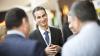Man smiling in conversation with three others at a reception