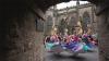 Dancers wearing colourful dresses perform next to a gothic church