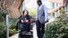 An employee in a wheelchair chatting to a colleague walking towards the office