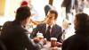 Three people sitting in a cafe drinking coffee and talking