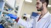 Male researcher in lab coat performing an experiment with test tubes