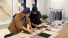 Two people at a desk overseeing many pieces of paper