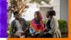Two women and a man sat outside having a conversation.