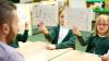 Children in a classroom holding up words written in French. 