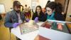 Three students examine a board game at the Museum of Childhood