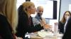 Person speaking into a microphone to a group at a table