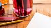 Coloured pencils, white paper and paint brushes in a pink glass on a wooden surface