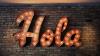 Spanish word for hello written in lights on brick wall