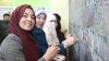 three women smiling writing on blackboard