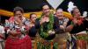 A still from the film Leitis in Waiting. It shows members of Leitis community from Tonga dancing to a song in elaborate colourful clothing and garlands. 