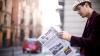 Man sitting outside in a city, looking at a copy of El País, a Spanish national newspaper.