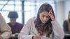 A woman sat taking and assessment, looking stressed.