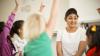 Teacher with children raising their hands