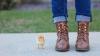 Person wearing boots standing next to a baby chicken