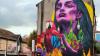 Artwork on the side of a building of a woman holding a parrot