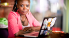 Woman sitting looking at the camera with a laptop open on a table in front of her.