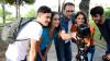 A group of young photography students on a course with their teacher. They are outdoors, looking at the camera. 
