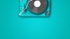 Modern record player seen from above on a turquoise surface 