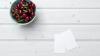Bowl of cherries and two pieces of paper on a table 