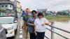 A male and two female researchers in an urban environment standing on a pavement next to a river