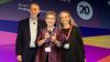 ELTons Awards host, Michael Rosen, standing on stage with Outstanding Achievement Award winner, Professor Penny Ur, who is holding the glass award trophy, and Dr Catherine Walter who presented the award. All smiling happily.