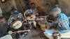 Three male musicians with wooden instruments watched by a researcher