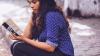 Woman in blue blouse sitting on step reading book