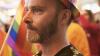 Man with tear in his eye wearing rainbow hat 