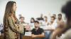 Woman delivering a presentation to a lecture hall full of students.