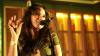 Female singer, singing into microphone at live event.