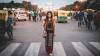 Woman standing on pedestrian crossing of busy road