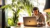 Man wearing headphones seated at a desk with a laptop. 