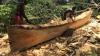 Two men carving out canoes