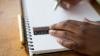 Young person's hands drawing a line in a notebook 
