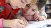 Two young girls writing in an exercise book