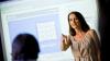 A teacher standing in front of an interactive white board talking to her class 