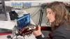 A girl student plays guitar to students in Uganda who watch via computer
