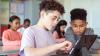 Two boys working together in class on a tablet.