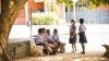 Students in Ghana gather together under a tree to chat