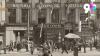 A sepia photograph from the 1940s showing the British Council Allied Centre in Liverpool. The building has flags hanging over the street, where people can be seen walking, and there is a man on a delivery bicycle, and a horse.