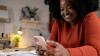 Woman sitting at a desk looking at her phone and smiling.