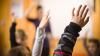 Children's hands raised in class.