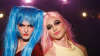 Sam and Alex the stars of Wait, Wait, Now. Sam is wearing a bright blue wig and Alex is wearing a pastel pink wig.